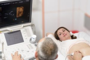 Doctor doing 3d ultrasound on belly of pregnant woman in clinic